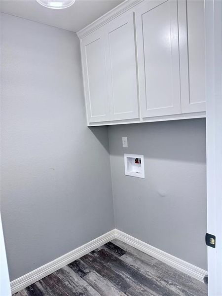 Washroom with dark wood-style floors, washer hookup, and cabinet space Washroom with dark wood-style floors, washer hookup, and cabinet space