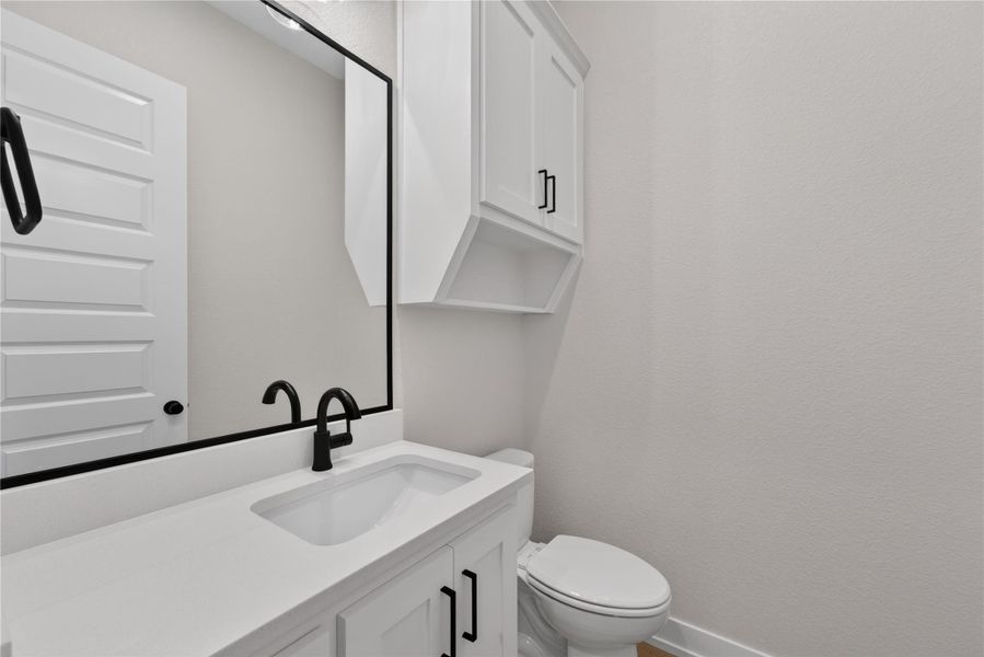 Clean lines and matte black fixtures define this updated powder room with custom cabinetry.
