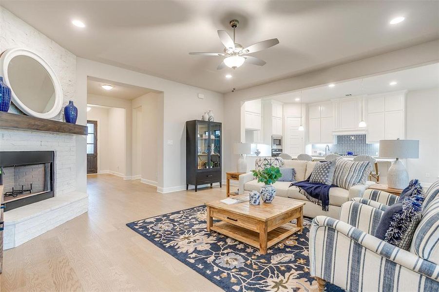 Living room featuring a fireplace, ceiling fan, and light hardwood / wood-style flooring