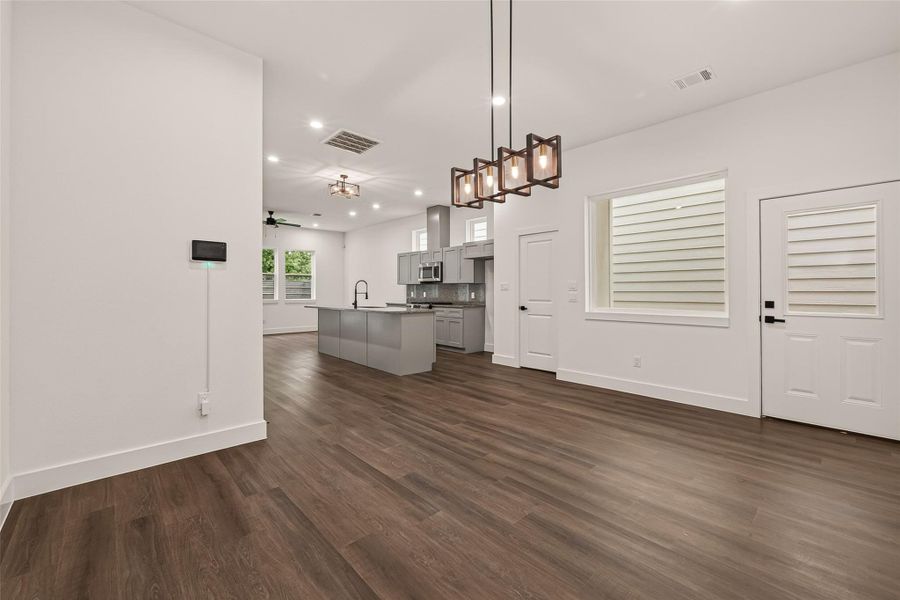 This modern open-concept living area features engineer wood flooring, a sleek kitchen with an island and stainless steel appliances, and ample natural light from large windows. Contemporary light fixtures add a stylish touch. This modern open-concept living area features engineer wood flooring, a sleek kitchen with an island and stainless steel appliances, and ample natural light from large windows. Contemporary light fixtures add a stylish touch.