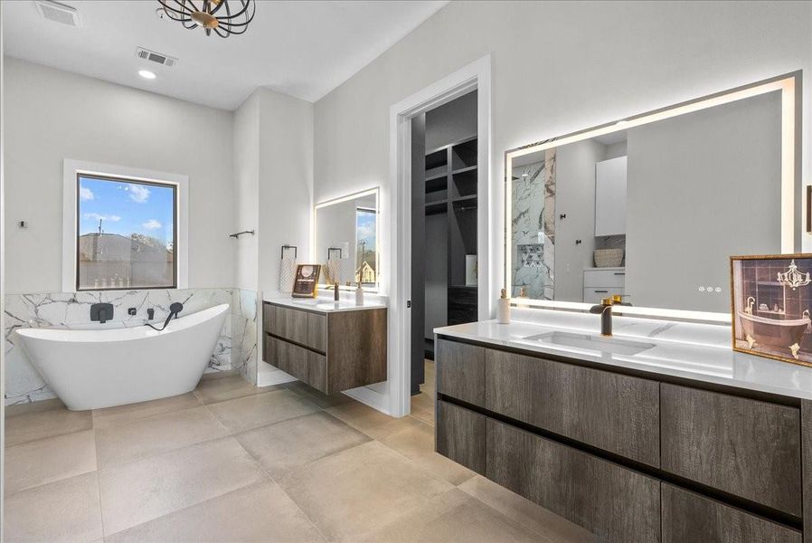 The primary bathroom feels like a private spa, featuring an oversized walk-in shower with multiple heads, a soothing rain feature, floor-to-ceiling porcelain tile, and a beautiful garden tub for relaxing at the end of the day.