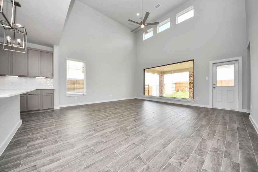Gather the family and guests together in your lovely living room! Featuring soaring high ceilings, recessed lighting, ceiling fan, custom paint, gorgeous floors, and large windows that provide plenty of natural lighting throughout the day.