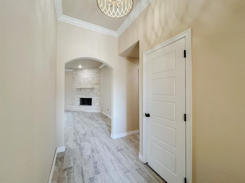 Hall featuring crown molding, light wood-type flooring, and arched walkways Hall featuring crown molding, light wood-type flooring, and arched walkways