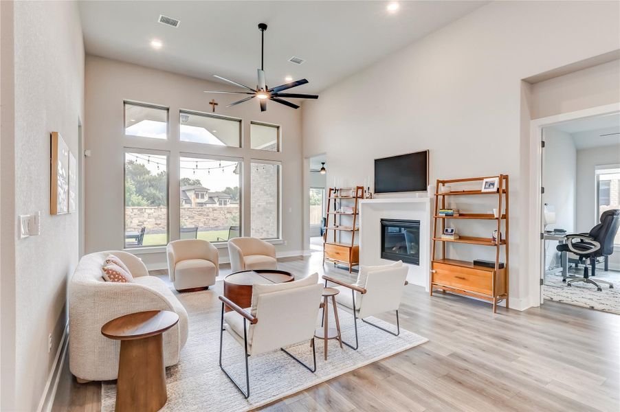 An airy living area with 14' ceilings offers towering windows and a welcoming fireplace, perfect for relaxation.