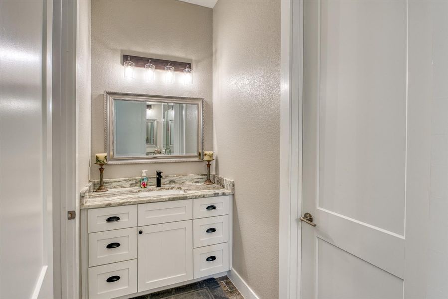 Bathroom featuring a textured wall and vanity