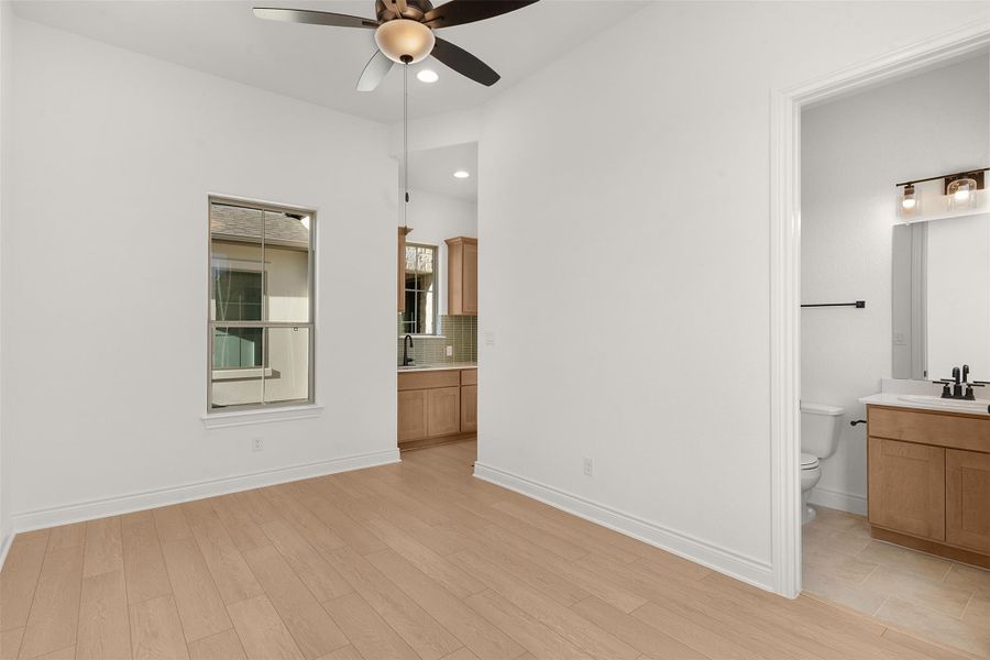 Unfurnished bedroom featuring connected bathroom, light wood finished floors, and ceiling fan