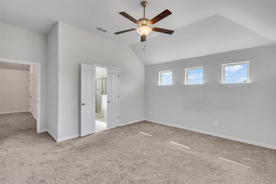 Unfurnished bedroom with ensuite bathroom, carpet flooring, lofted ceiling, and ceiling fan