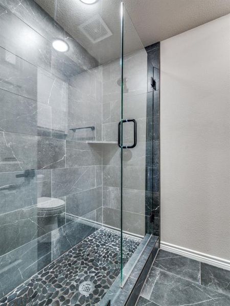 Full bath with a stall shower, baseboards, marble finish floors, and toilet Full bath with a stall shower, baseboards, marble finish floors, and toilet