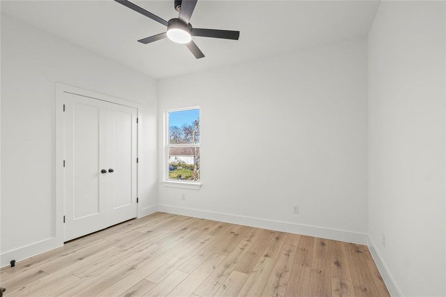 Unfurnished bedroom featuring light wood-style floors, ceiling fan, and a closet