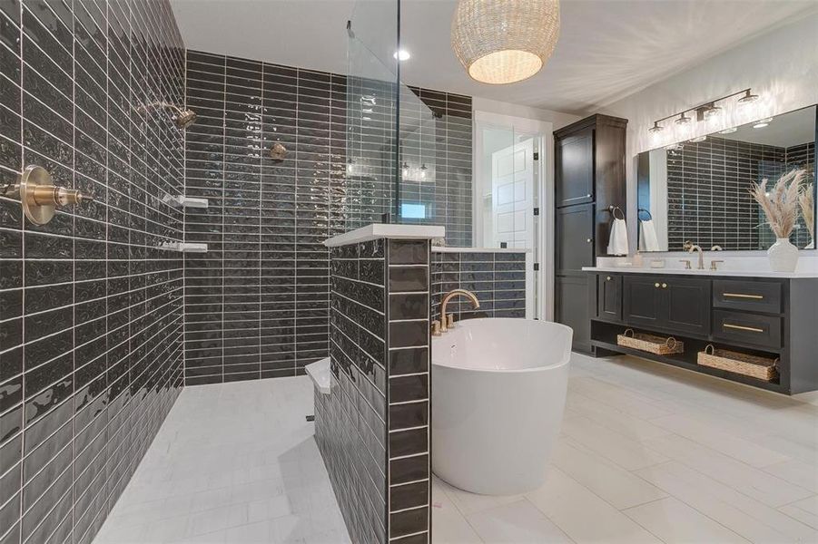 Bathroom featuring tile patterned flooring, shower with separate bathtub, vanity, and tile walls