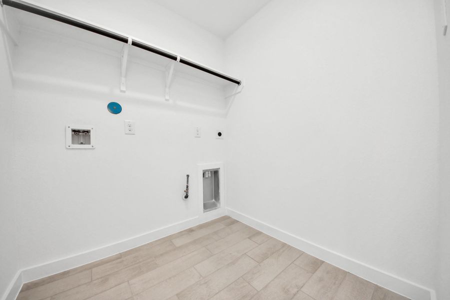 A perfect blend of functionality and comfort. Capture the essence of easy living with a first-floor laundry room, thoughtfully equipped with shelving for effortless organization. Both electric and gas connections available. Sample photo of completed home with similar floor plan. Actual colors and selections may vary.