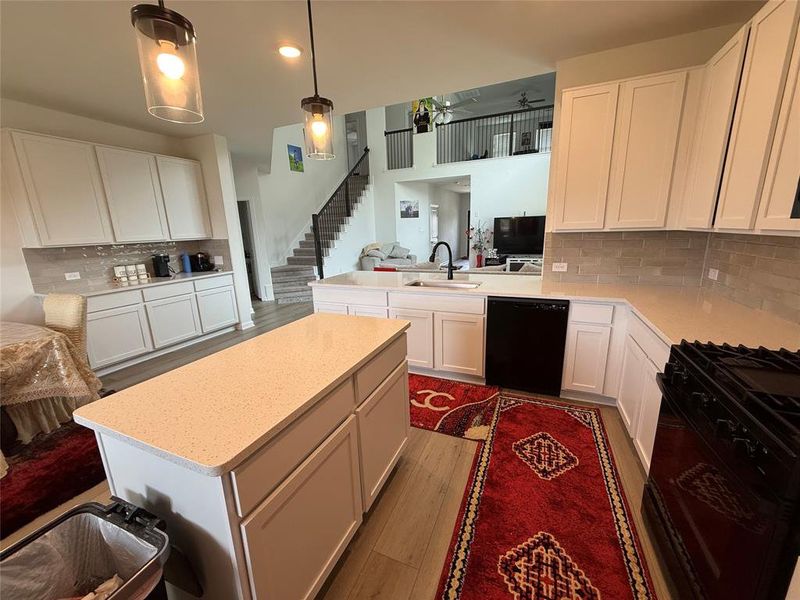 Kitchen featuring a central island with a light-toned countertop, white cabinetry, and wood-finish flooring