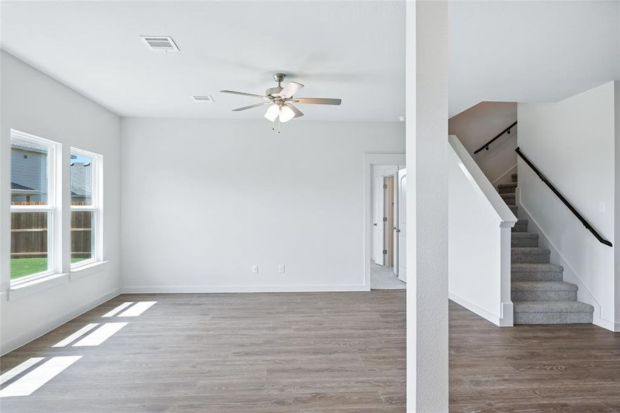 Unfurnished living room featuring wood finished floors, stairway, and a ceiling fan Unfurnished living room featuring wood finished floors, stairway, and a ceiling fan