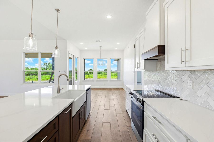 A pristine kitchen boasts an expansive island with a farmhouse sink and gleaming countertops, perfectly illuminated for culinary creations.