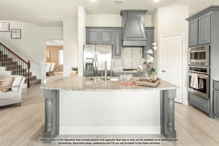 Kitchen with large granite island, gray cabinets, decorative range hood, and stainless steel appliances