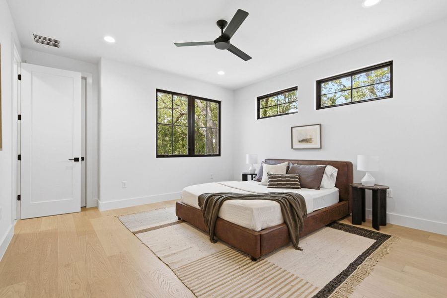Crisp white walls and warm wood flooring define this peaceful, modern sleeping space.