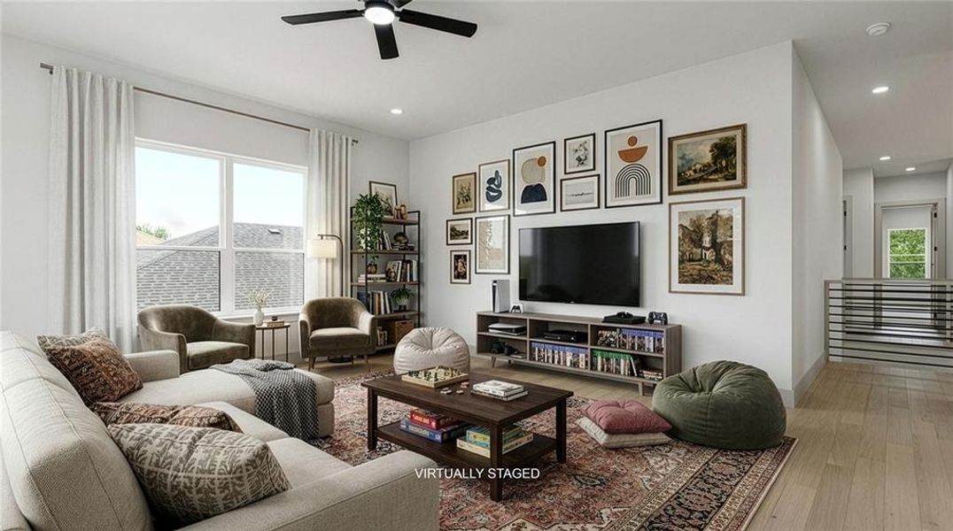 Spacious interior game room on the second level featuring light wood-finish flooring, a large window, recessed lighting, a ceiling fan, and a hallway with a horizontal metal railing. Spacious interior game room on the second level featuring light wood-finish flooring, a large window, recessed lighting, a ceiling fan, and a hallway with a horizontal metal railing.