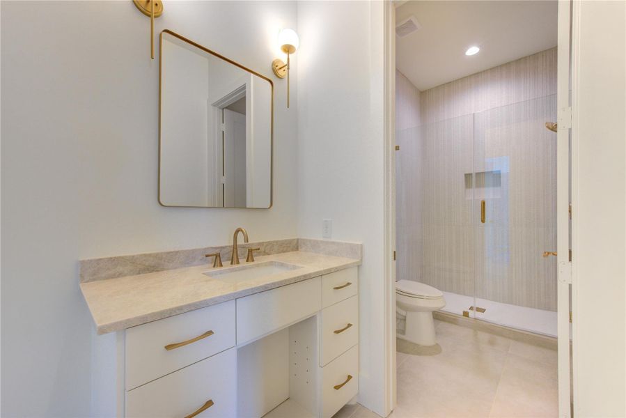 The third secondary ensuite bath is thoughtfully designed with the same elevated level of craftsmanship found throughout the home. Designer-selected finishes, custom cabinetry, premium stone countertops, and elegant plumbing fixtures create a polished and inviting space. Light-filled and beautifully appointed, this private bath offers comfort and convenience while maintaining the home's cohesive luxury aesthetic.