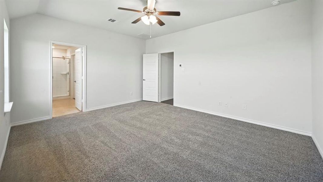Spacious room featuring vaulted ceilings, a ceiling fan with light fixture, light gray carpeting, and white baseboards Spacious room featuring vaulted ceilings, a ceiling fan with light fixture, light gray carpeting, and white baseboards