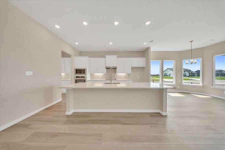 Kitchen with stainless steel appliances, light wood finished floors, a large island, light countertops, and recessed lighting Kitchen with stainless steel appliances, light wood finished floors, a large island, light countertops, and recessed lighting