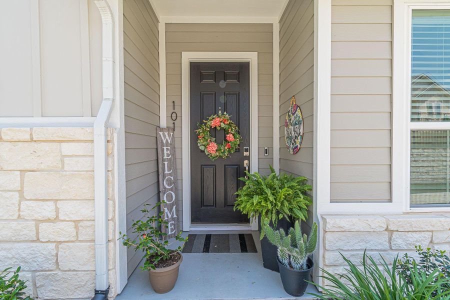 View of exterior entry featuring stone siding and covered porch