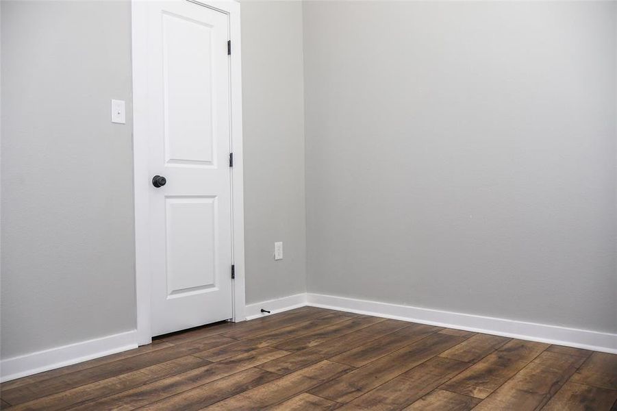 Empty room featuring dark wood-type flooring and baseboards Empty room featuring dark wood-type flooring and baseboards