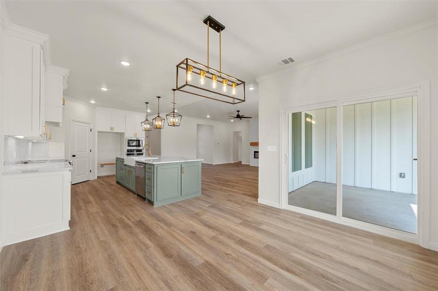 Kitchen with green cabinetry, white cabinetry, ornamental molding, an island with sink, and open floor plan Kitchen with green cabinetry, white cabinetry, ornamental molding, an island with sink, and open floor plan
