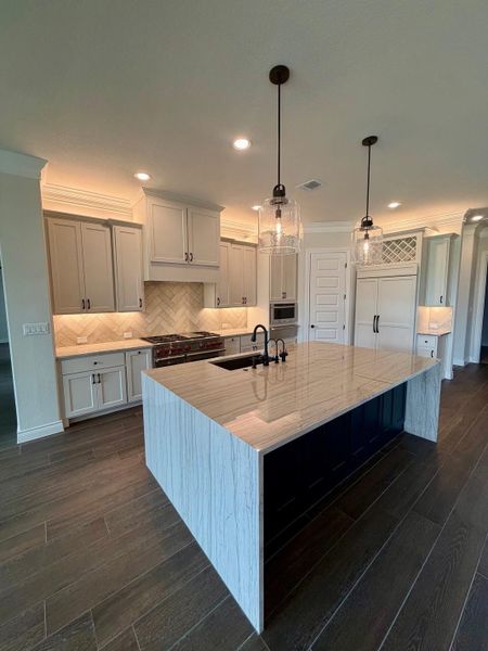 Polished stone surfaces and custom cabinetry define this thoughtfully crafted kitchen space.