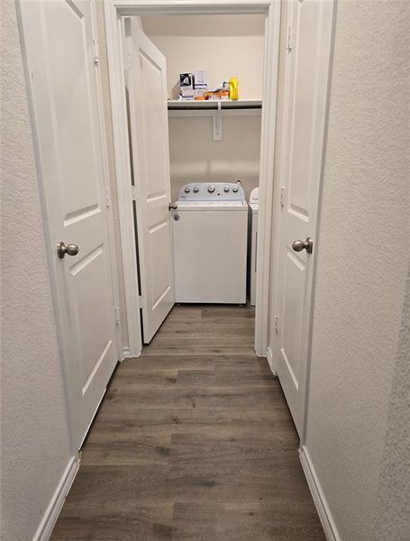 Washroom with dark hardwood / wood-style flooring and independent washer and dryer