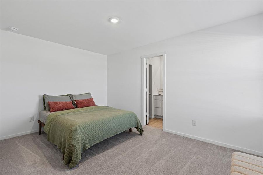 Bedroom with light colored carpet and ensuite bathroom