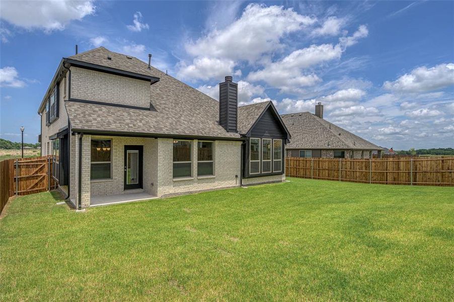 Back of property featuring a fenced backyard, a patio, a shingled roof, brick siding, and a chimney