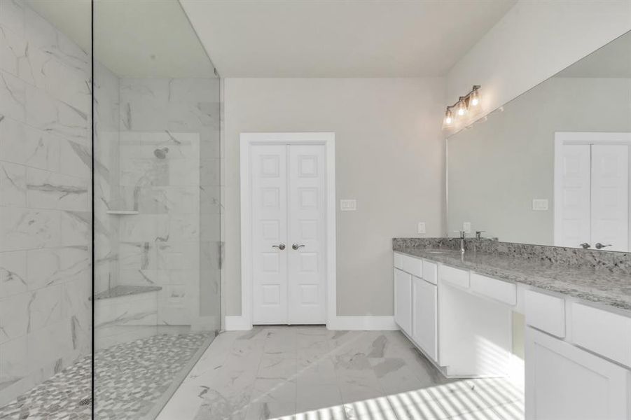 Luxurious walk-in shower, featuring spacious bench seating for added comfort and indulgence. A perfect blend of style and functionality, creating a spa-like retreat in the comfort of your own home. Sample photo of completed home with similar floor plan. As-built interior colors and selections may vary.