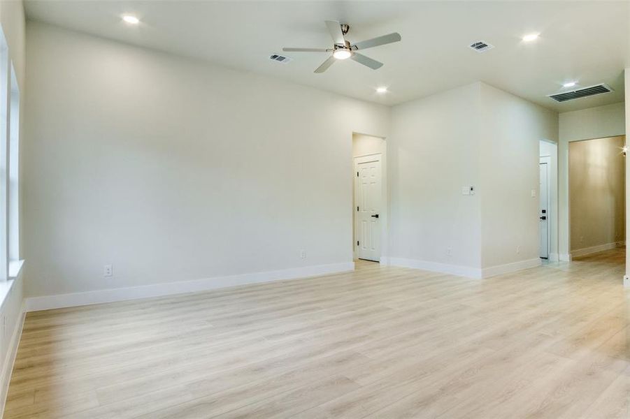 Spare room featuring visible vents, light wood-style flooring, ceiling fan, and baseboards