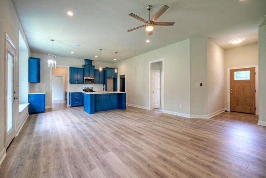 Kitchen featuring blue cabinetry, open floor plan, light wood-type flooring, recessed lighting, and light countertops