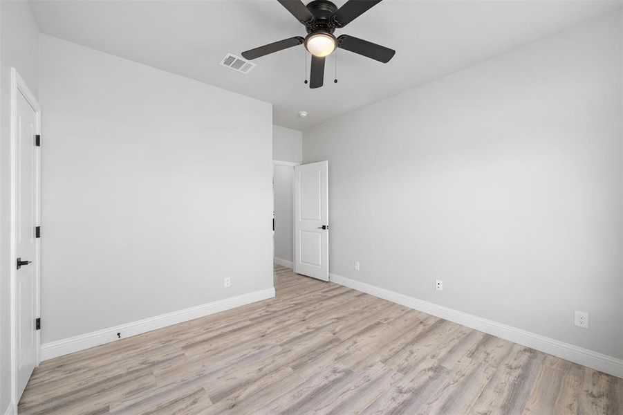 Unfurnished bedroom with ceiling fan, baseboards, visible vents, and light wood-type flooring