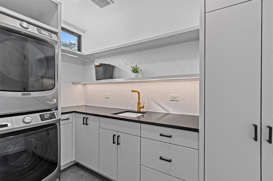 Laundry room with plenty of extra storage, a sink and stackable high-end appliances that convey.