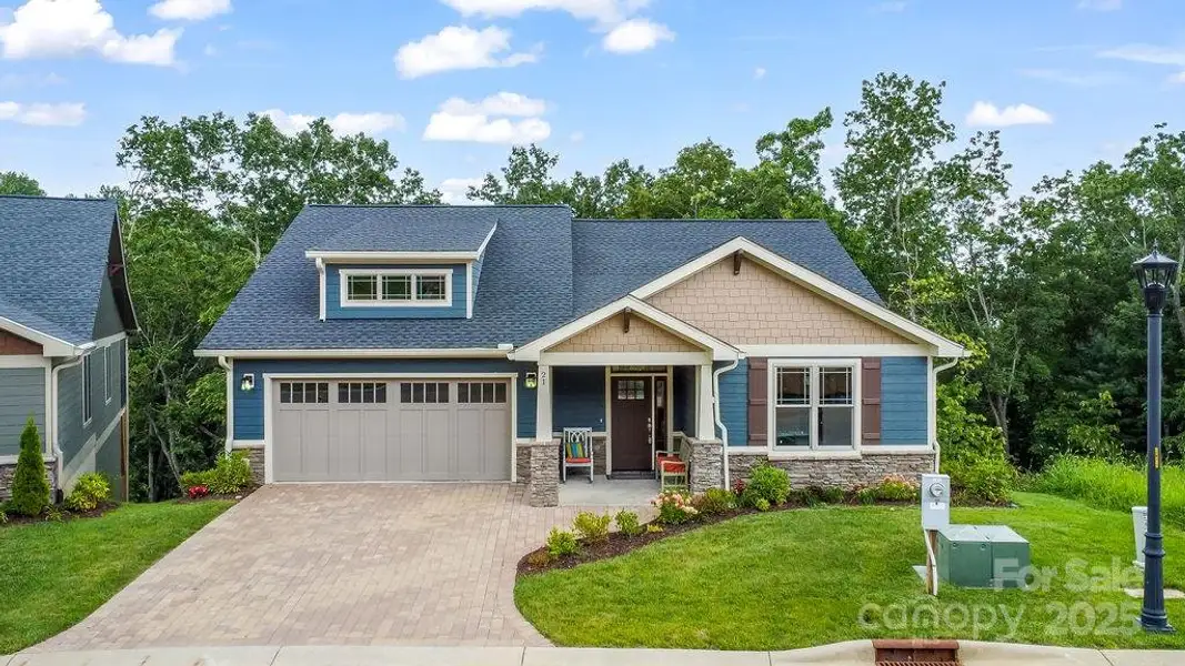 Handsome façade featuring stonework, paver driveway, and Craftsman charm