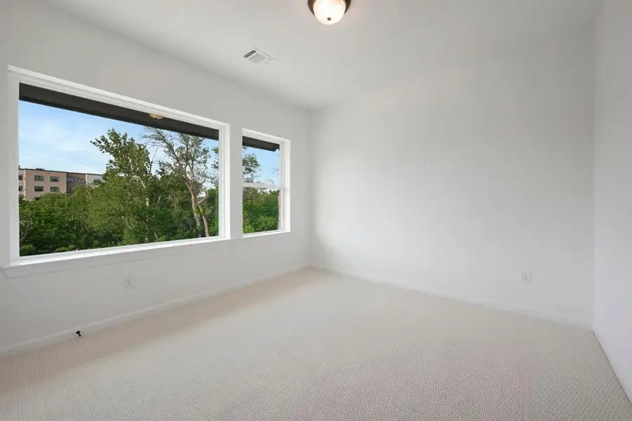 Bright room featuring two large windows, white walls, light-toned carpeting, and a flush-mount ceiling light fixture