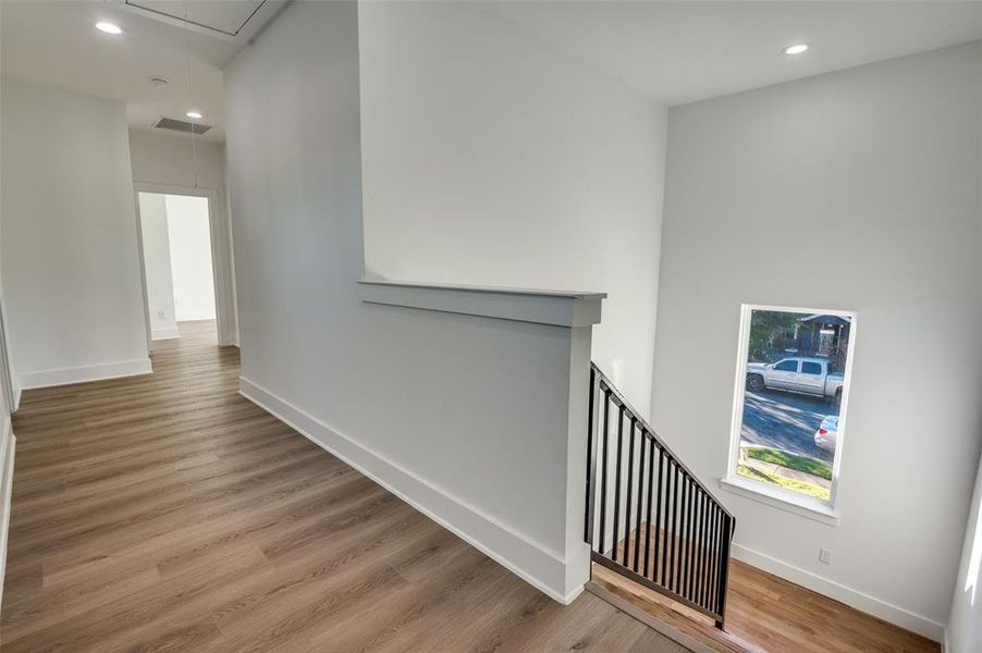 Corridor featuring recessed lighting, attic access, light wood-style flooring, and an upstairs landing