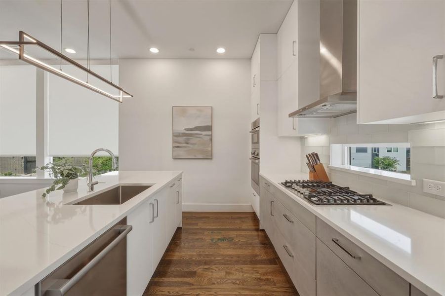 Kitchen featuring light stone countertops, modern cabinets, stainless steel appliances, dark wood finished floors, and white cabinets
