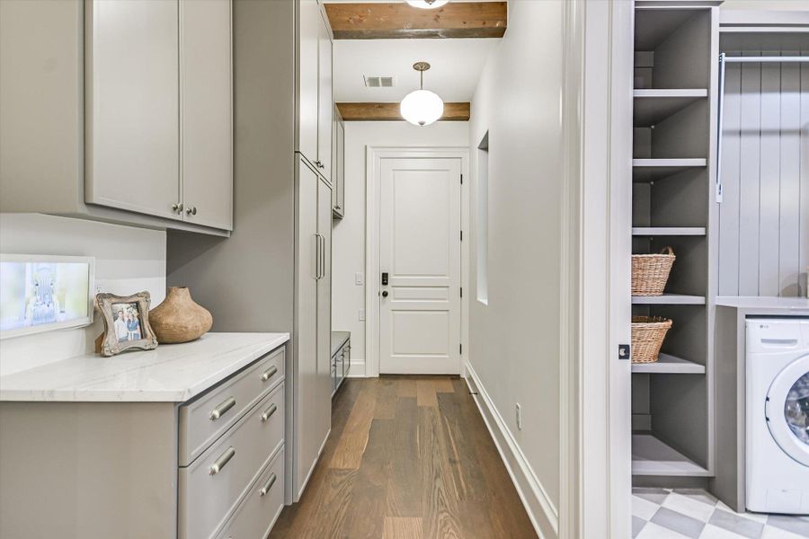 Laundry room featuring washer / clothes dryer, beamed ceiling, and dark wood finished floors Laundry room featuring washer / clothes dryer, beamed ceiling, and dark wood finished floors
