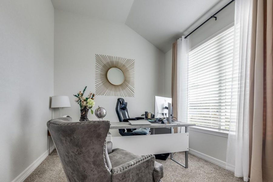 This cozy home office features a large window with elegant curtains, providing ample natural light. Creating a productive yet stylish environment.