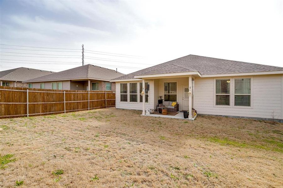 Back of house with a shingled roof, fence private yard, and a patio