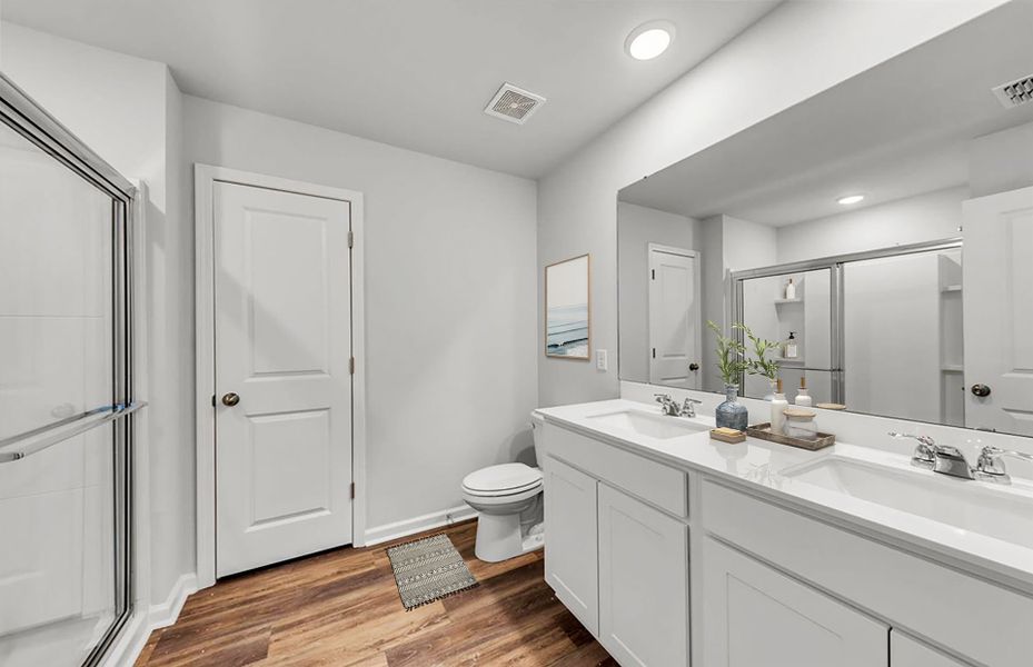 Private Owner's Bath with a walk-in shower and timeless wood flooring.