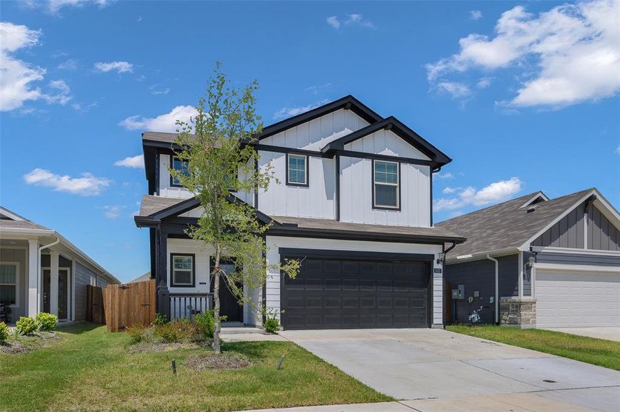 Two-story residence featuring a black-on-white exterior, a two-car garage, a covered front porch, a concrete driveway, and a fenced side yard Two-story residence featuring a black-on-white exterior, a two-car garage, a covered front porch, a concrete driveway, and a fenced side yard