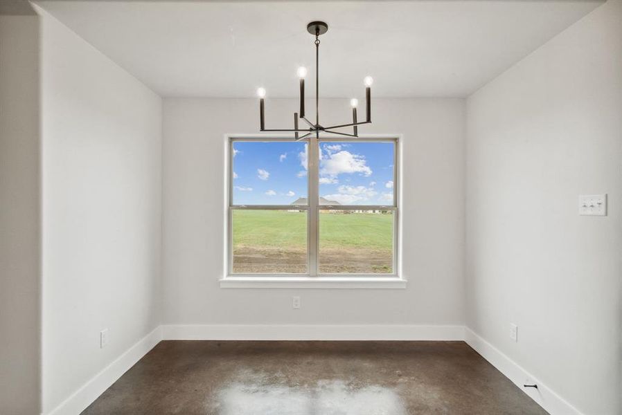 Unfurnished dining area with an inviting chandelier and concrete flooring