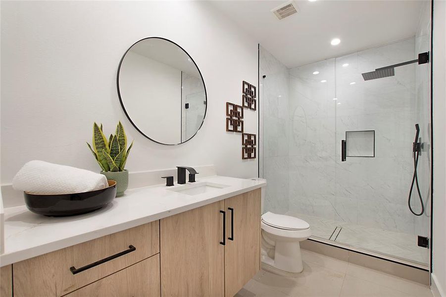 Bathroom with a shower with door, vanity, toilet, and tile patterned floors