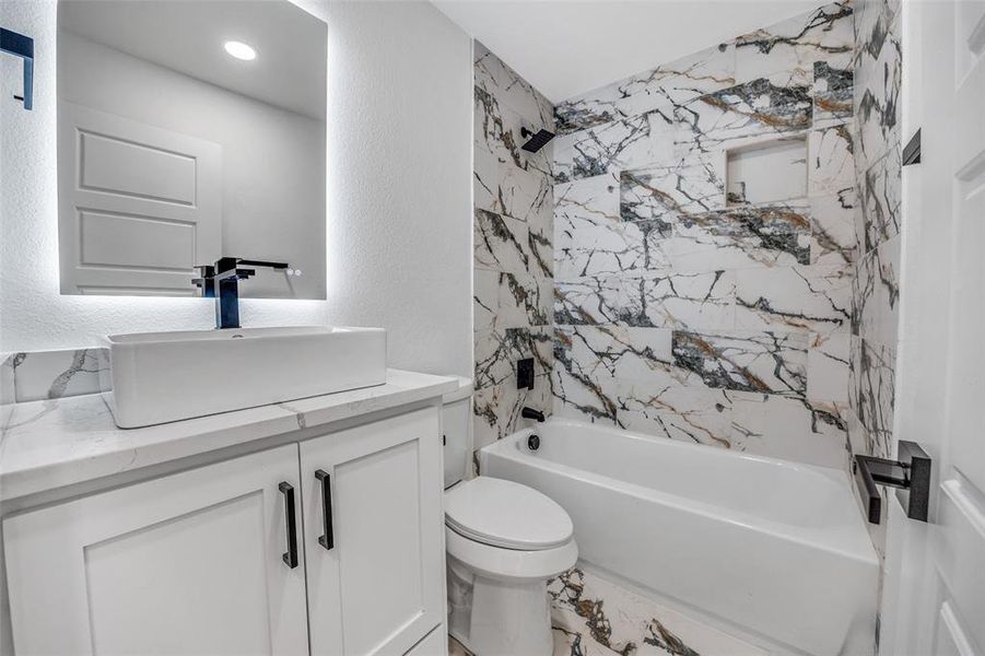 Full bathroom with shower / washtub combination, vanity, and a textured wall Full bathroom with shower / washtub combination, vanity, and a textured wall