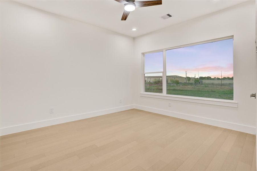 Bright third bedroom with large window and clean modern design.