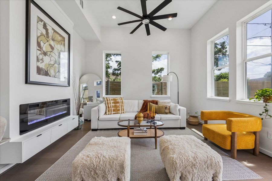 Light filled living room featuring soaring ceilings, expansive windows, a sleek linear fireplace, and an open layout designed for everyday living and entertaining. Light filled living room featuring soaring ceilings, expansive windows, a sleek linear fireplace, and an open layout designed for everyday living and entertaining.